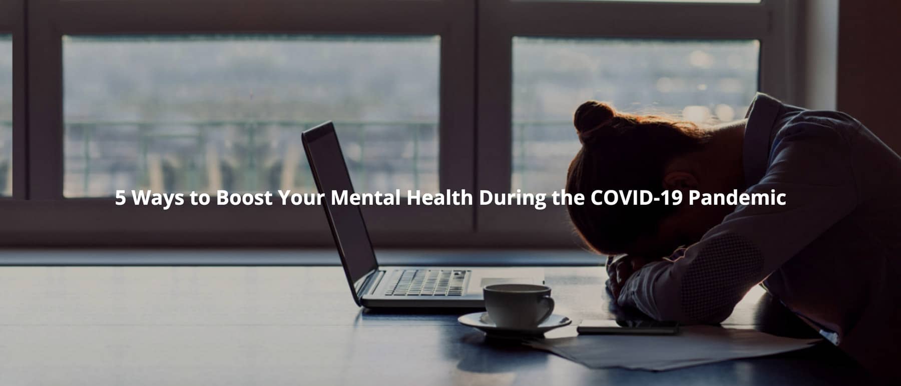 woman laying her head down on desk while working in front of laptop