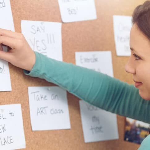 young woman pinning notes on a bulletin board